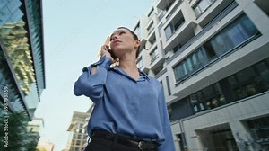 Woman realtor talking cellphone looking on residential district. Lady calling