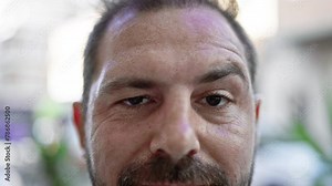 Close-up portrait of a confident middle-aged man with grey hair in an urban outdoor setting.