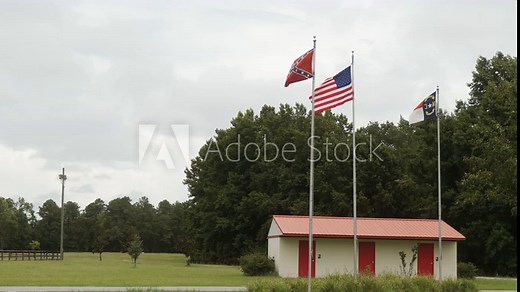 US, confederate civil war, and the North Carolina State flags waving in the wind over an historic Civil War battle field