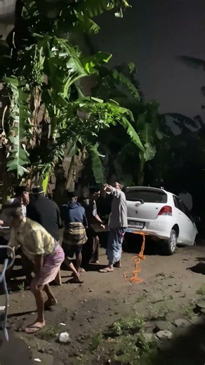 Men Pulling Stuck Car Topple Backward as Rope Snaps