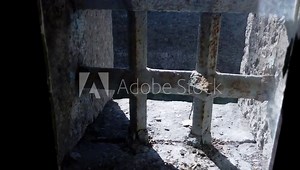 Backing away from vintage iron barred prison window in confined concrete cell