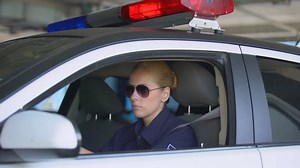 clip-1033112711-female-police-officer-taking-off-sunglasses-seat