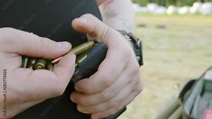 man's hands loading a pistol magazine. man loads the clip of pistol.