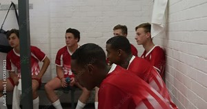 Coach talking to rugby players in the locker room