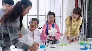 science teacher giving students Learn about microorganisms in test tubes To bring the camera and microscope to the elementary school science class, a group of students were excited to learn.