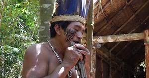 Native Brazilian playing wooden flute at an indigenous tribe in the Amazon