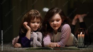Two little sisters are reading an interesting book