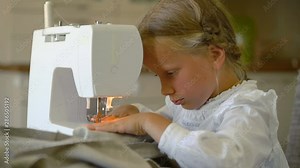 seven year old girl sews at home on a sewing machine