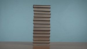 Stop motion video in which light hits a stack of old books on a wooden table.