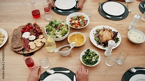 Hands, food on table for thanksgiving and people together in home for celebration event of tradition. Family, party or gathering with an adult group in an apartment, bonding over meal from above