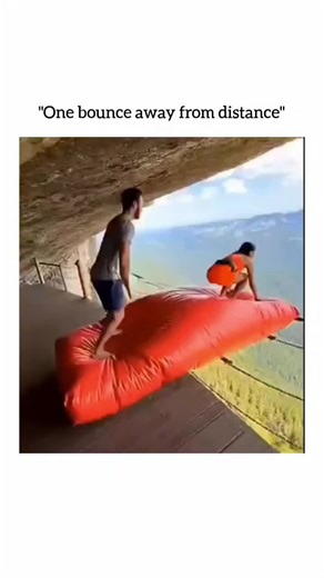 ONLY FUN on Instagram: "The video shows an extreme stunt set in a mountainous landscape, where a woman is launched off a cliff on a red inflatable blob. She bounces once along a wire-guided path before landing safely on a clearly marked pad. The audio captures excited commentary, including: “Ready? Set it! She is flying! Yes, perfect shot. Nailed it.” Credit & Source : The earliest version located was shared on X on December 23, 2025, by @casmirtheking_. It is unclear whether this is the origina