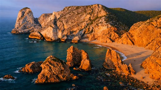 Dramatic rock formations rising from a quiet coastal shore