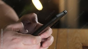 adult man is sitting in office at workplace and writing message on a smartphone. Close-up of a man's fingers dialing a number on a cell phone. Modern wireless technology. Online business or shopping.