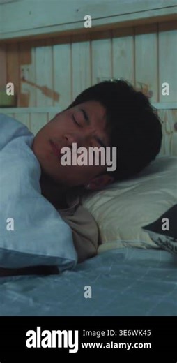 asian man sleeping in bed, soft blue bedding and wooden headboard, green candle on shelf, closeup of face shifting Stock Video Footage - Alamy
