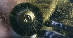 Super Slow Motion of Polishing Brush in Action with Gold Dust Flying in the Air - Macro of Rotating Abrasive Tool Used for Jewelry Finishing in Workshop at 1000 fps.