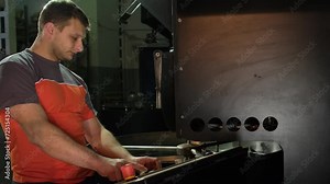 Engineer oversees roasting machine operating control panel. Operator well-versed in coffee production technology configures settings for machine