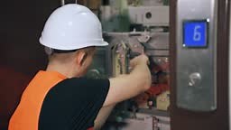 A utility worker repairs an elevator in a residential complex. A...
