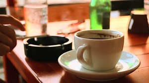 Girl drinking coffee in the cafe bar and smoke a cigarette