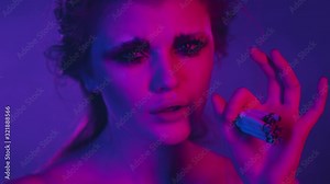 sad young pretty girl in pink and purple neon rays with fashion makeup and hair style smoking pack of cigarettes at once, overdose of nicotine concept