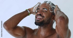 Smiling young adult handsome african man washing head with anti-dandruff shampoo taking shower. Happy hipster afro american guy enjoying everyday fresh clean hair care routine. Male haircare concept.