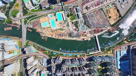 Aerial skyview of Tuen Mun subway extension project in Hong Kong, featuring elevated railway construction along Tuen Mun River and road, new station development and temporary work platforms