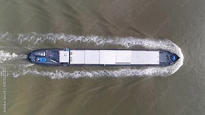 Aerial top down view of barge moving over water this flat-bottomed boat is mainly built for river and canal transport of heavy goods most barges are self-propelled steady footage 4k resolution