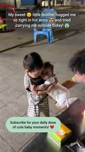 Hilarious little boy holds baby brother in tight hug while dad watches! 👀
