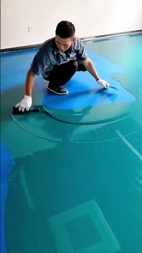 Epoxy floor coating application creating a smooth glossy blue finish