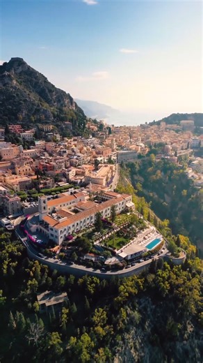 6.3K views · 105 reactions | Taormina is calling your name 朗 This Sicilian gem is spectacularly perched on the side of a mountain and overlooks the sparkling sea below. Between its magnificent natural landscapes, you also have the opportunity to soak in the old world atmosphere of the famous resort town — from chic boutiques to its 2,500-year-old ancient Greek theater.  IG: adrianbaias | See Italy Travel | Facebook