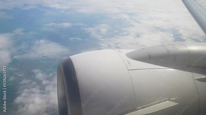 View From Airplane Window Showcasing Engine and Clouds During Daytime Travel. View outside plane window captures stunning expanse of clouds beneath wing and engine