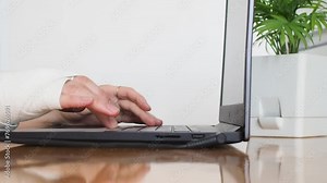 Female hand wrapped in elastic bandage typing on a laptop computer keyboard. Manager with one broken wrist works the Internet at home.