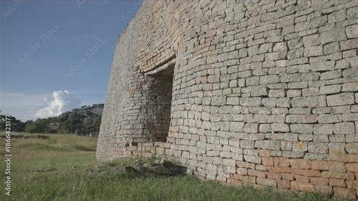 Great Zimbabwe African ruins and monument landmark of ancient civilization in slow motion with historic stone structure and village beneath hill complex at enclosure archaeological site travel spot