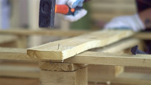 Removing a crooked nail from a plank of wood using a crowbar - Free Stock Video