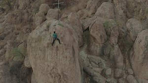 Mountaineer climbing to the top of a large rock - Free Stock Video