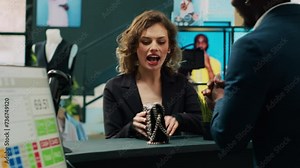 African american retail clerk scanning barcode on bag at cash register, preparing items for customer at department store. Young woman choosing trendy accessories from showroom. Camera A.