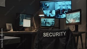 No people shot of security guard workspace with CCTV video footage on monitors, landline phone, walkie-talkie and flashlight