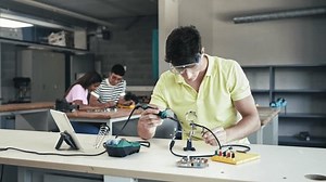 College Student working on electronics circuit, learning science technology in robotics course - Digital Innovation in Education
