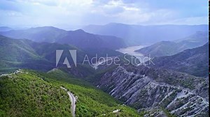 Beautiful nature, countryside scenery with dramatic hilly terrain, mountain peaks, green forest and water lake, blue sky clouds horizon, aerial forward motion wide view