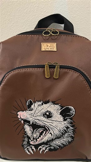 The opossum you loved last year is back! 🐾 Now on our new structured backpack Embroidered vegan leather Limited quantities at Pensacon#handcrafted #pensacon #pensacola | Sew Nerdy Bags