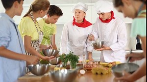 Two chefs teach children how to cook food - they beat eggs with a whisk. High quality 4k footage