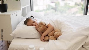 Cute caucasian girl sleeping sweet on white soft pillows under blanket and hugging her teddy bear friend. Pretty kid with two braids regaining energy during disease at home.