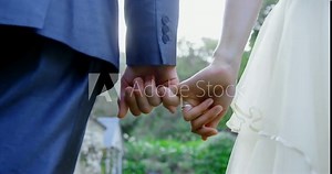 Groom holds little finger of bride