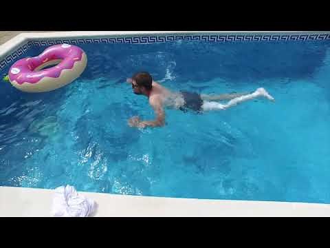 Boy with long leg cast swimming in the pool, try to go on crutches with both broken legs