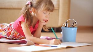 clip-33221776-little-girl-draws-pictures-lying-on-floor