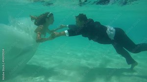 UNDERWATER: The bride and groom holding hands under the water, Indian Ocean, Maldives
