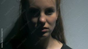 A young woman looks and smiles mischievously at the camera. Her gaze becomes angry and she spits on the lens. Filmed from close up.