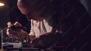 Man solders Transistors, RadioElectronic Parts on Electronic Board with Soldering Iron.Repairing a microcircuit, smoke from soldering iron.Disconnect radio components.Scheme with precious metal, gold.