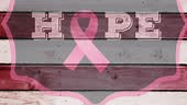 Animation of pink ribbon logo with breast cancer text over wooden...