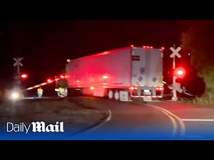 Terrifying moment driver's truck is hit by train after getting stuck on railway tracks
