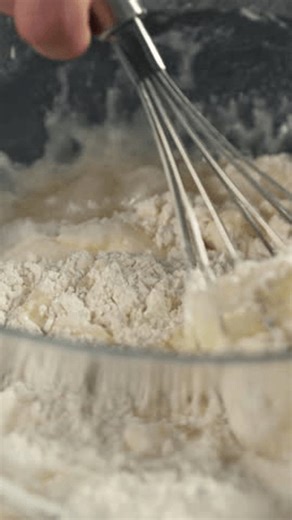 clip-4004505339-vertical-view-flour-mix-eggs-using-whisk